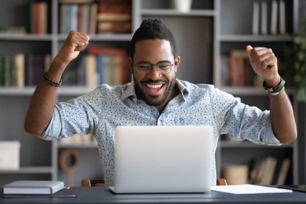 istock Happy african guy looking at pc screen scream with joy 1253877142