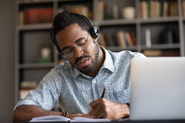 istock Focused african student writing notes listening lecture studying online 1253877166