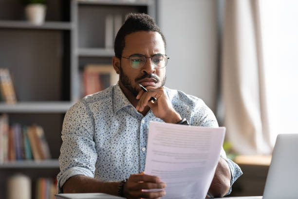 abogado masculino africano leer detalles del contrato se siente concepto descontento - looking at papers fotografías e imágenes de stock