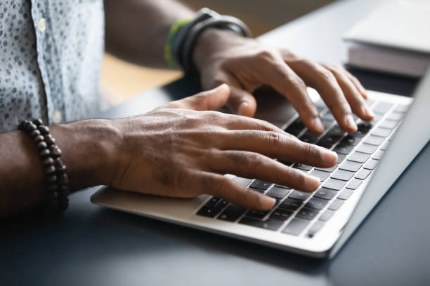 istock Closeup image african male hands typing on laptop keyboard 1253877411