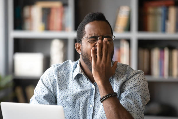 istock African man sitting at workplace yawns feels unmotivated 1253877734