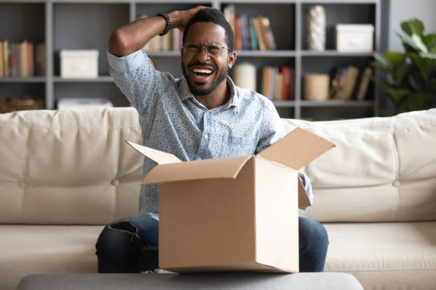 istock Laughing African guy overjoyed opening cardboard box 1253877763