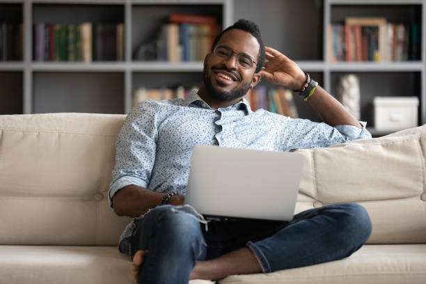 istock African guy seated on couch with laptop looking at camera 1253877779