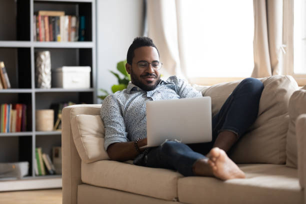 istock African guy lying on couch use notebook chatting with friends 1253877782