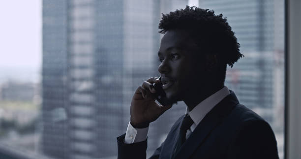 istock African ethnicity businessman using smartphone. City panorama 1253877801