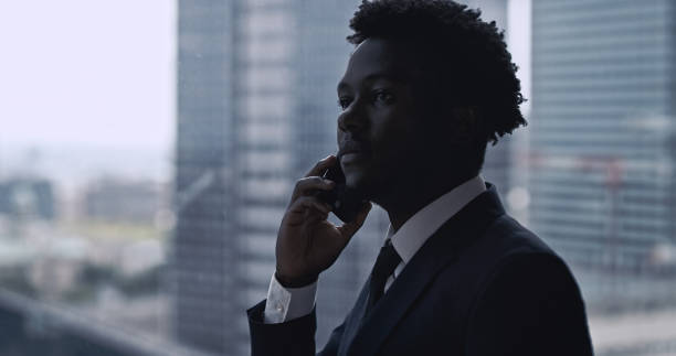 istock African ethnicity businessman using smartphone. City panorama 1253877819