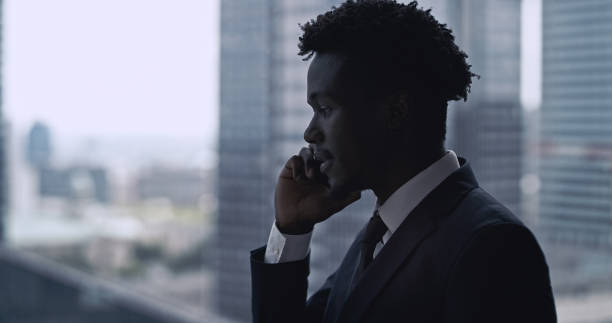 istock African ethnicity businessman using smartphone. City panorama 1253877831
