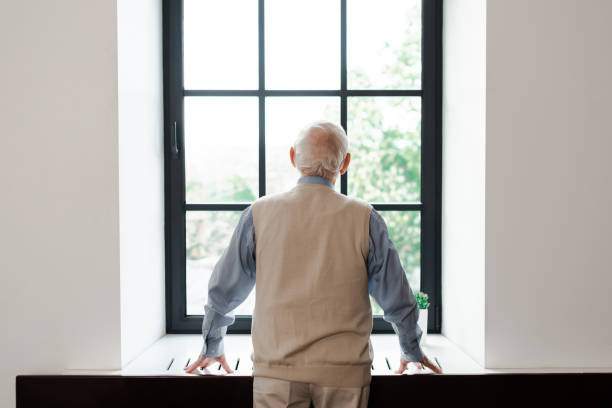 istock back view of lonely elderly man standing near window during quarantine 1253878340