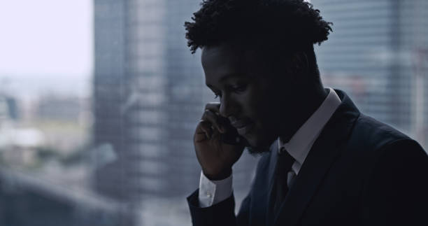 istock African ethnicity businessman using smartphone. City panorama 1253878401