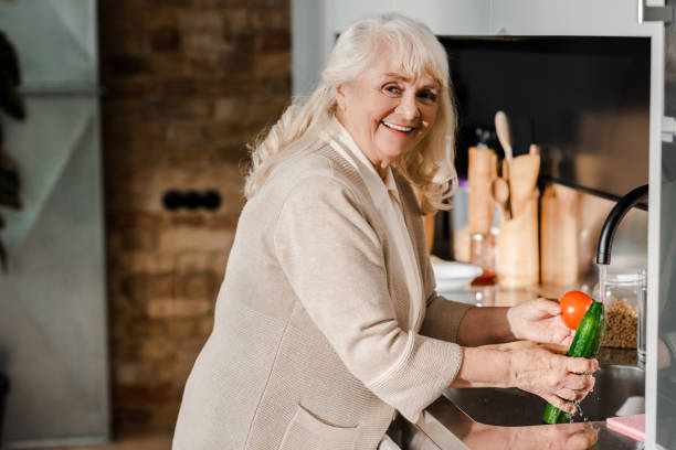 istock happy senior woman washing vegetables on kitchen 1253878408