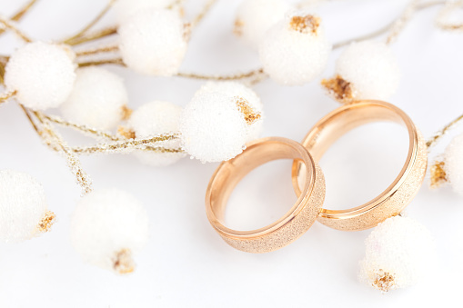 Light Elegant wedding background - two golden rings and decorations on white background