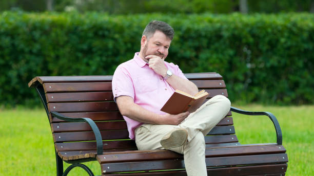 istock Caucasian man in a red shirt is reading a book. 1253881270