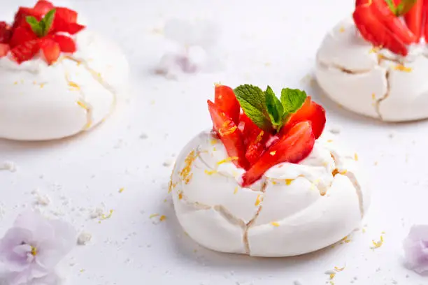 Photo of Homemade meringue dessert Pavlova cake with fresh strawberries and mint. Summer dessert. French cake. Confectionery. Classic dessert. Strawberry dessert