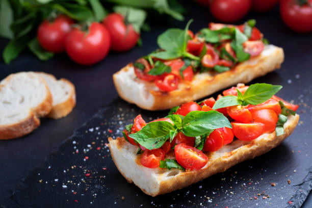 Homemade bruschetta with cherry tomatoes and basil closeup on a slate board. Italian cuisine. Antipasti. Vegan food stock photo
