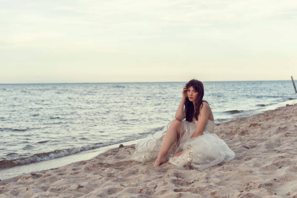 istock Bride in a white dress by the sea 1253887375