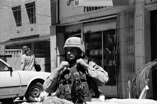 Portrait of a US soldier sitting at his machine gun and monitoring a street in Baghdad and the surroundings. Iraq during the Gulf War between the USA and Iraq. Photographed by Michael Multhoff in Baghdad / Iraq. May 12, 2003
