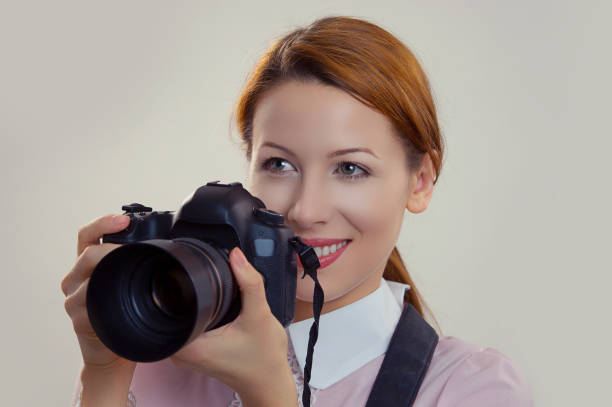 istock Photographer. Woman smiling, holding camera. 1253888836