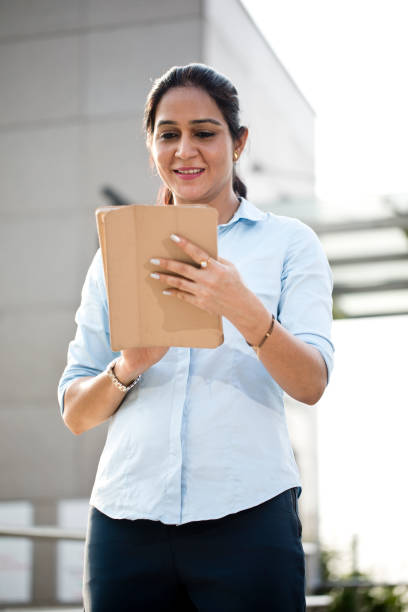 istock Businesswoman using digital tablet outside office building 1253891420