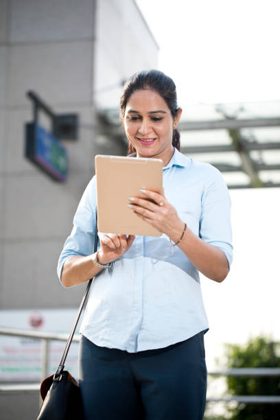 istock Businesswoman using digital tablet outside office building 1253891565