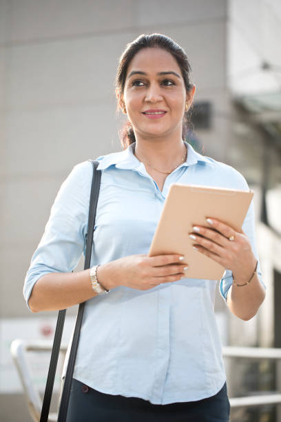 istock Businesswoman using digital tablet outside office building 1253891602