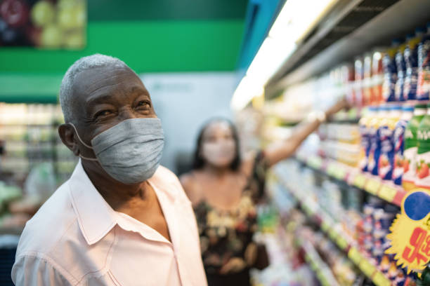 Portrait of senior man with face mask shopping at supermarket Portrait of senior man with face mask shopping at supermarket convenience store photos stock pictures, royalty-free photos & images