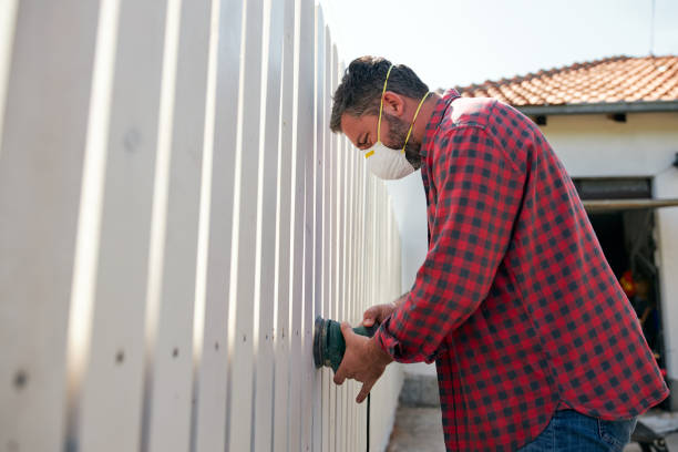 istock Man using an electric sander while sanding the wooden fence 1253895104