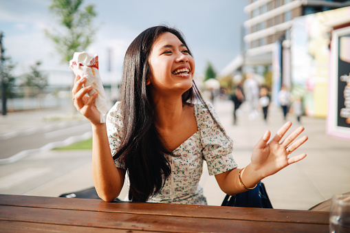 Young woman sitting in the outdoors café and eating ice cream.