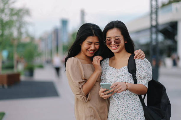 istock Two girls using phone on the promenade 1253895696