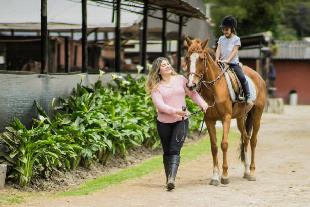 giovane madre che insegna a sua figlia passeggiate a cavallo - teaching child horseback riding horse foto e immagini stock