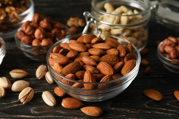 istock Bowls with different nuts on wooden background. Vitamin food 1253897469
