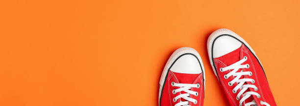 istock Pair of red sneakers on orange background, space for text 1253898761