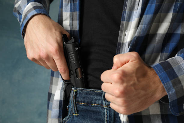 istock Man takes out a gun from jeans, close up. Robber 1253900082