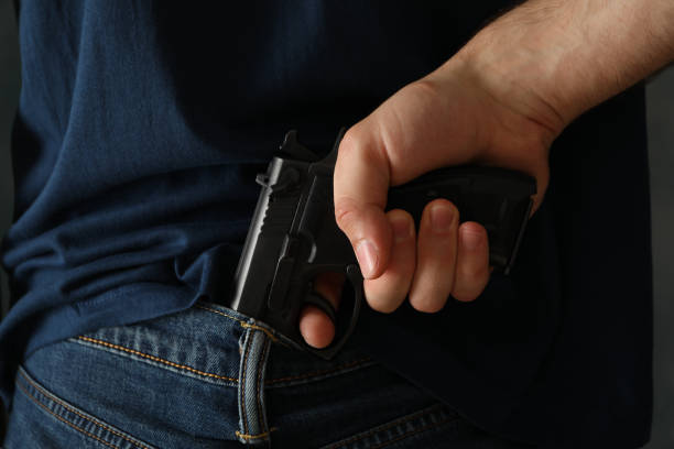 istock A man hold a gun from behind. Self defense weapon 1253900172