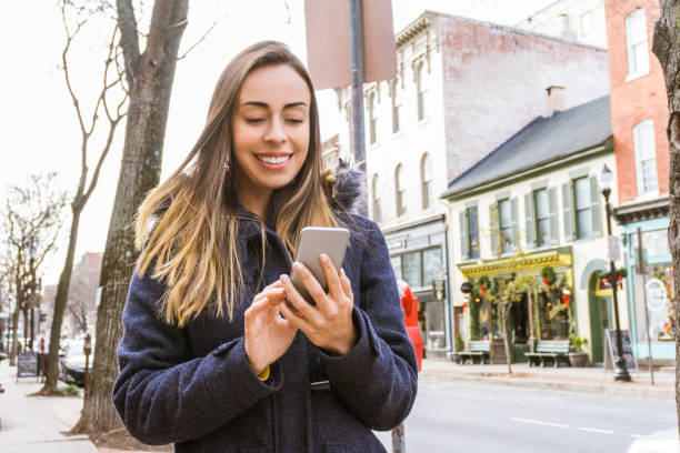 istock Young woman texting on her smartphone while walking down the street 1253901256