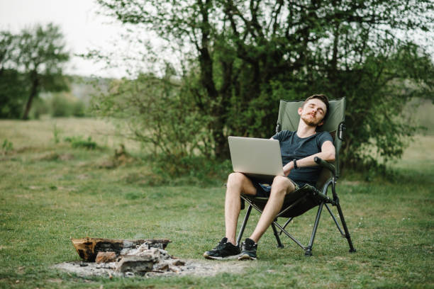 istock Male relaxing and work on vacation. Young man using online banking for sending money everywhere. Male traveler blogger work remote on the laptop computer while enjoying nature. 1253904257