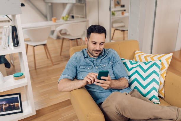 istock Young man relaxing in his cozy chair and using phone 1253904359