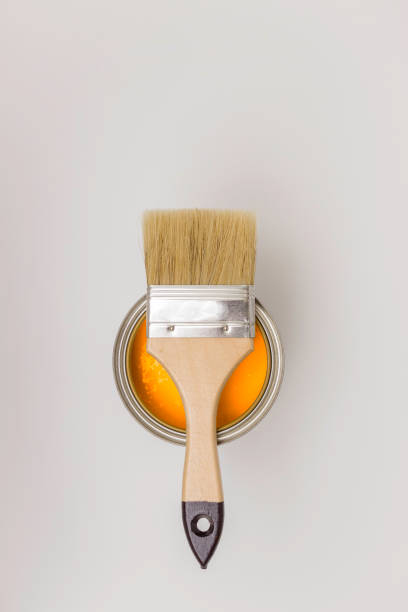 istock Paintbrush on a Bank with orange paint, light background, top view. 1253905590