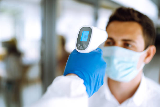 istock Hand in glove holding ir thermometer. 1253907450