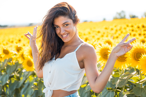 A beautiful influencer in a sunflower field celebrates the arrival of summer and the end of the pandemic