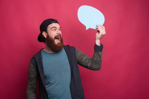 istock Happy excited man is holding and looking at a small blue bubble speech over red background 1253913603