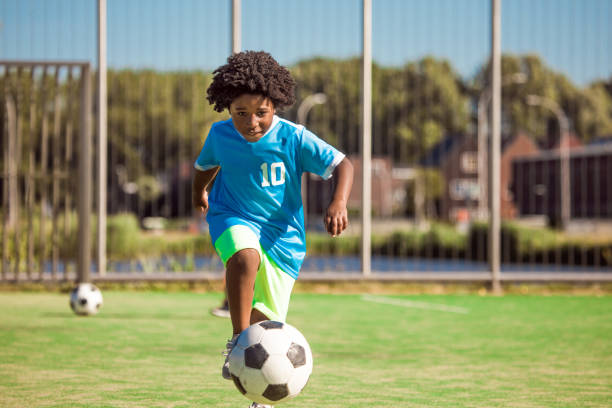 istock Beautiful young black boy training on the football pitch 1253913708