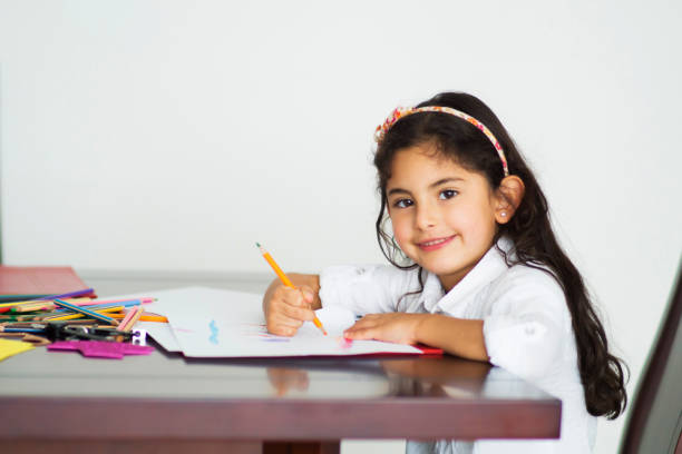 istock Beautiful latin american girl doing homework facing camera smiling 1253914064