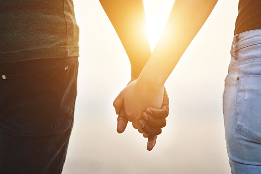 Closeup shot of an unrecognisable couple holding hands outdoors
