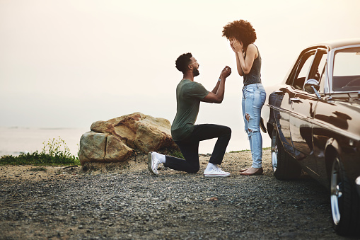 Shot of a young man proposing to his girlfriend during a road trip