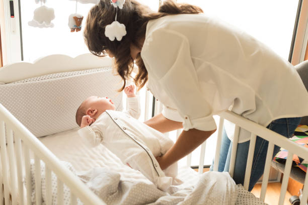 mutter legt baby schlafen - phone cradle stock-fotos und bilder