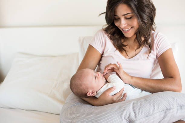 Mother with baby Young mother with baby in bed breastfeeding photos stock pictures, royalty-free photos & images