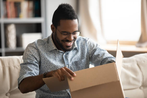 istock African man opening parcel seated on couch at home 1253929846