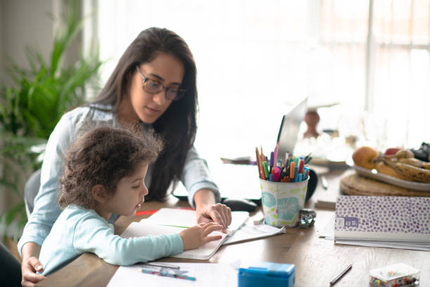 istock Mother helps young girl home school while working 1253933503