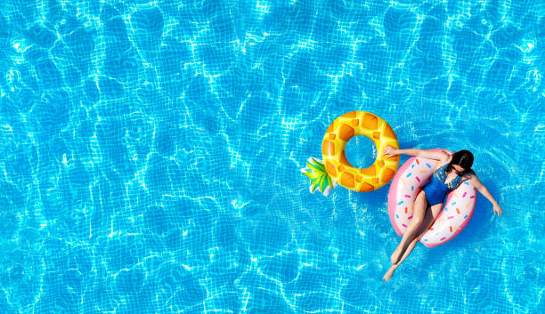 Pool water texture background with a woman on the inflatable water toys. Directly above. Top view from drone. Pool water texture background with a woman on the inflatable water toys. Directly above. Top view from drone. inflatable photos stock pictures, royalty-free photos & images
