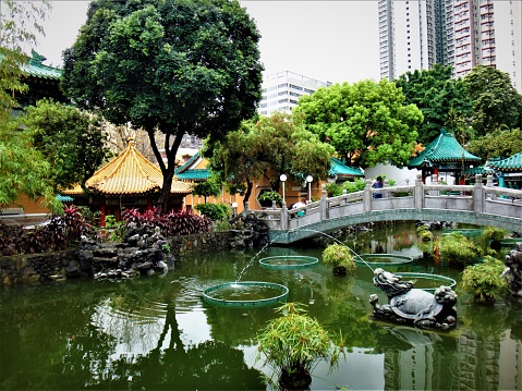 Hong Kong, Hong Kong - April 2, 2014: Amazing Chinese garden reflecting in a tranquil pond at a temple in Hong Kong